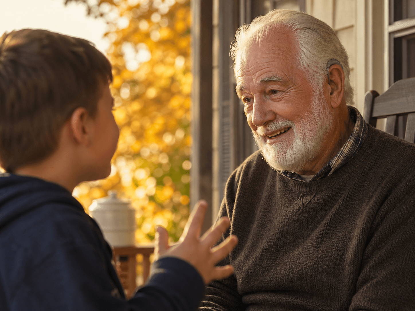 Grandfather smiling and listening attentively to his grandson on a sunlit autumn porch